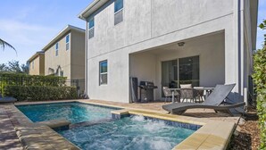 Uma casa moderna com piscina, área de estar externa e um alpendre.