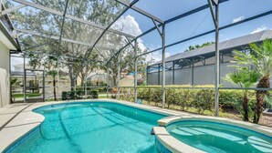 A swimming pool with a glass enclosure, surrounded by greenery and a clear sky. - Mediterranean Style Family Villa Close To Disney (Kissimmee)