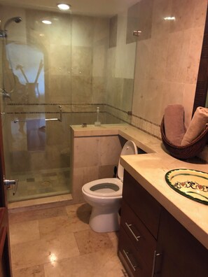 Ein Badezimmer mit einer Duschkabine, einer Toilette und einem Waschtisch mit Handtuchhalter.
