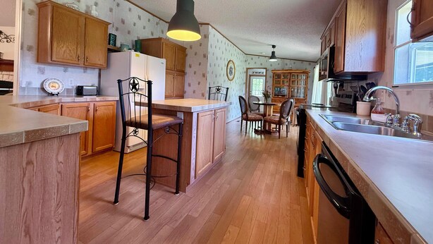 Una cocina con armarios de madera, un refrigerador, un microondas y un comedor con sillas y una mesa.