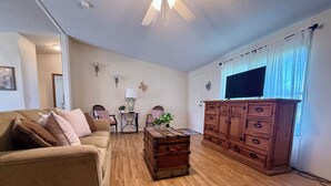 Una sala de estar con sofá, sillones, aparador de madera, televisor y ventilador de techo.
