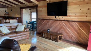 A cozy living room with a leather sofa, a wooden coffee table, and a flat-screen TV mounted on the wall.