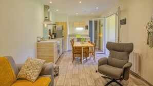Ein gemütlicher Wohnraum mit Küchenzeile, Essbereich und einer Sitzecke mit Sofa und Sessel.