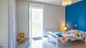 Ein Schlafzimmer mit einem Bett, einem Sessel, einem Fenster und einer Deckenleuchte.