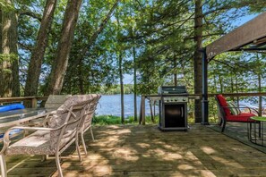 A covered deck with a grill, outdoor furniture, and a view of a lake. - Traverse City LAKE Front Cottage15 Min to Downtown Front St. PET Friendly GRILL (Traverse City)