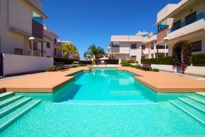 Une piscine entourée de bâtiments modernes, avec des marches menant à l’eau.