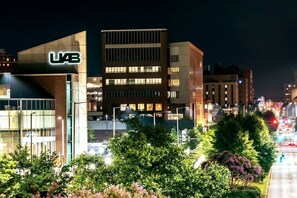 A modern building with a prominent 'UB' sign, surrounded by trees and a busy street at night. - A Place to Esape too (Birmingham)