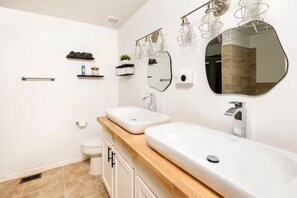 A modern bathroom with two sinks, a toilet, and a mirror. - A Place to Esape too (Birmingham)