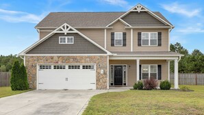 A two-story house with a stone facade, a garage, and a front porch. - Spacious Family Retreat Near Camp Lejeune, Swansboro & Hammocks Beach (Hubert)