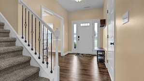 A hallway with a wooden staircase, a white door, and a small table. - Spacious Family Retreat Near Camp Lejeune, Swansboro & Hammocks Beach (Hubert)