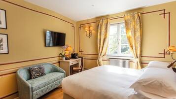 Une chambre d’hôtel équipée d’un lit, d’un bureau, d’une chaise, d’une télévision et d’une fenêtre avec des rideaux.