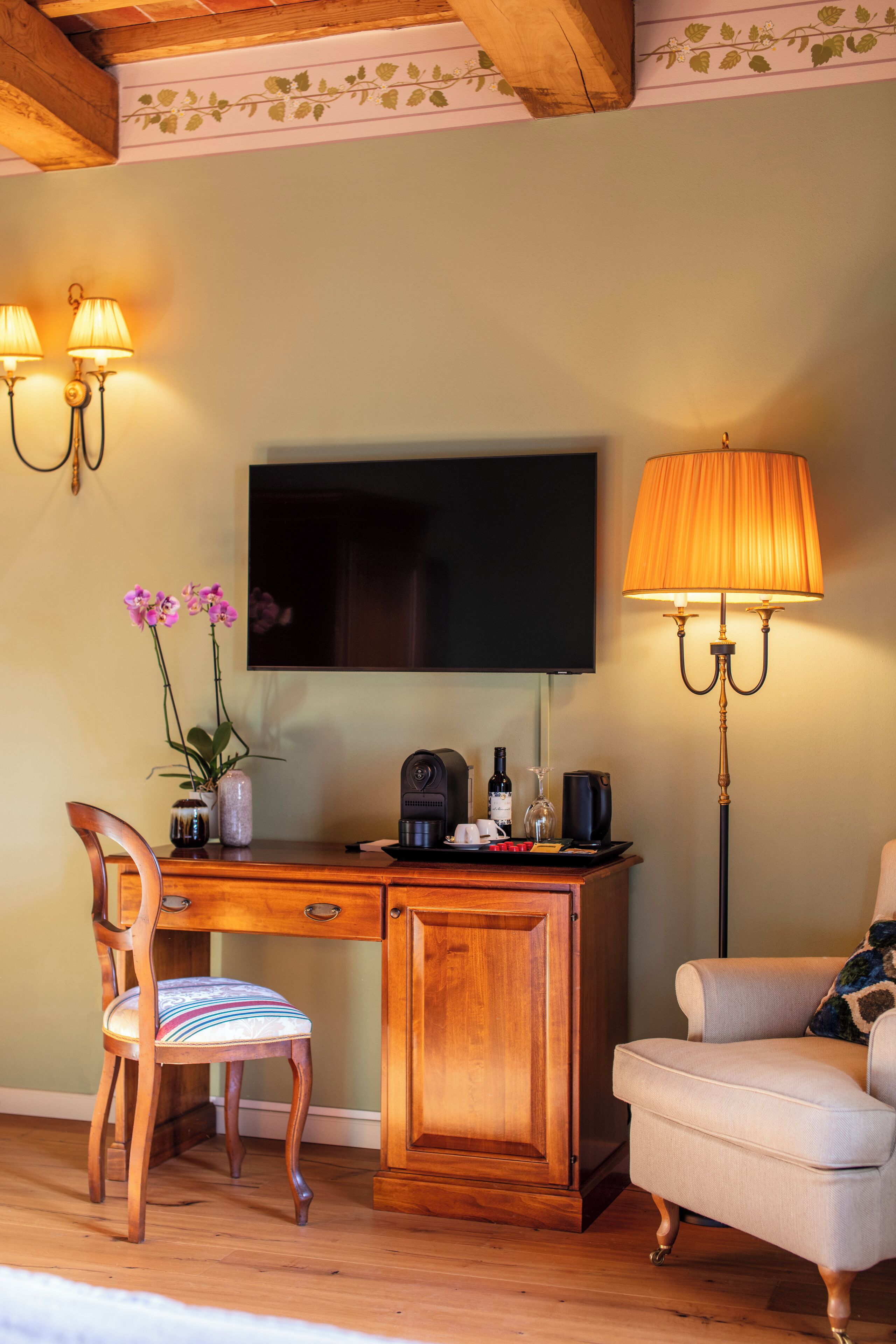 A wooden desk with a television, a lamp, and a chair with a cushion.