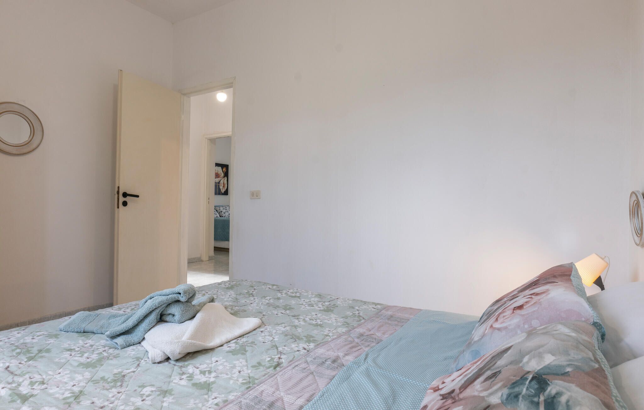 A bedroom with a bed, a door, and a light fixture.