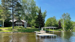 Una propiedad frente al lago con muelle, un pabellón y una casa con tejado inclinado.
