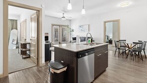 Une cuisine moderne dotée d’un îlot central, d’appareils électroménagers en acier inoxydable et d’un coin repas avec une table en forme de croix.