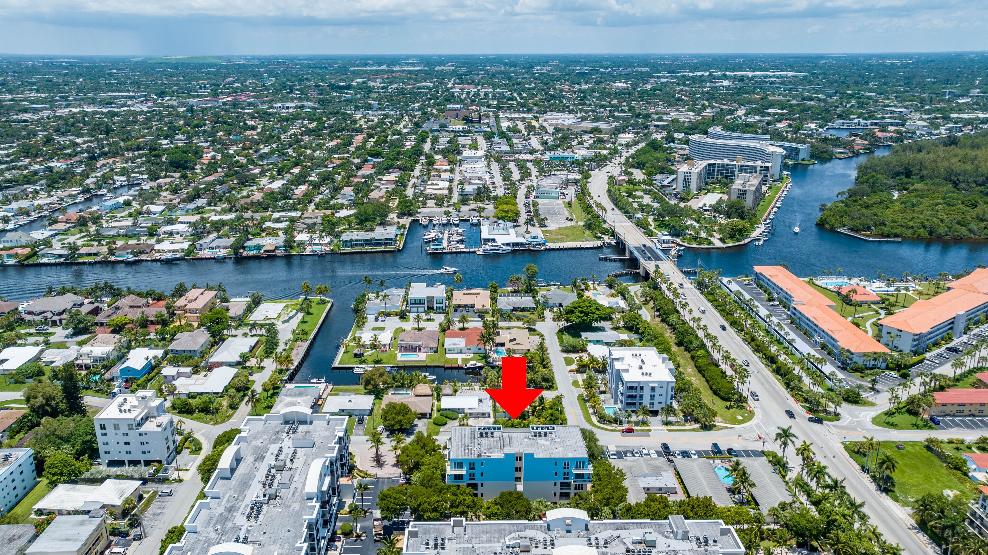 An aerial view of a coastal city with a marina, residential areas, and commercial buildings.