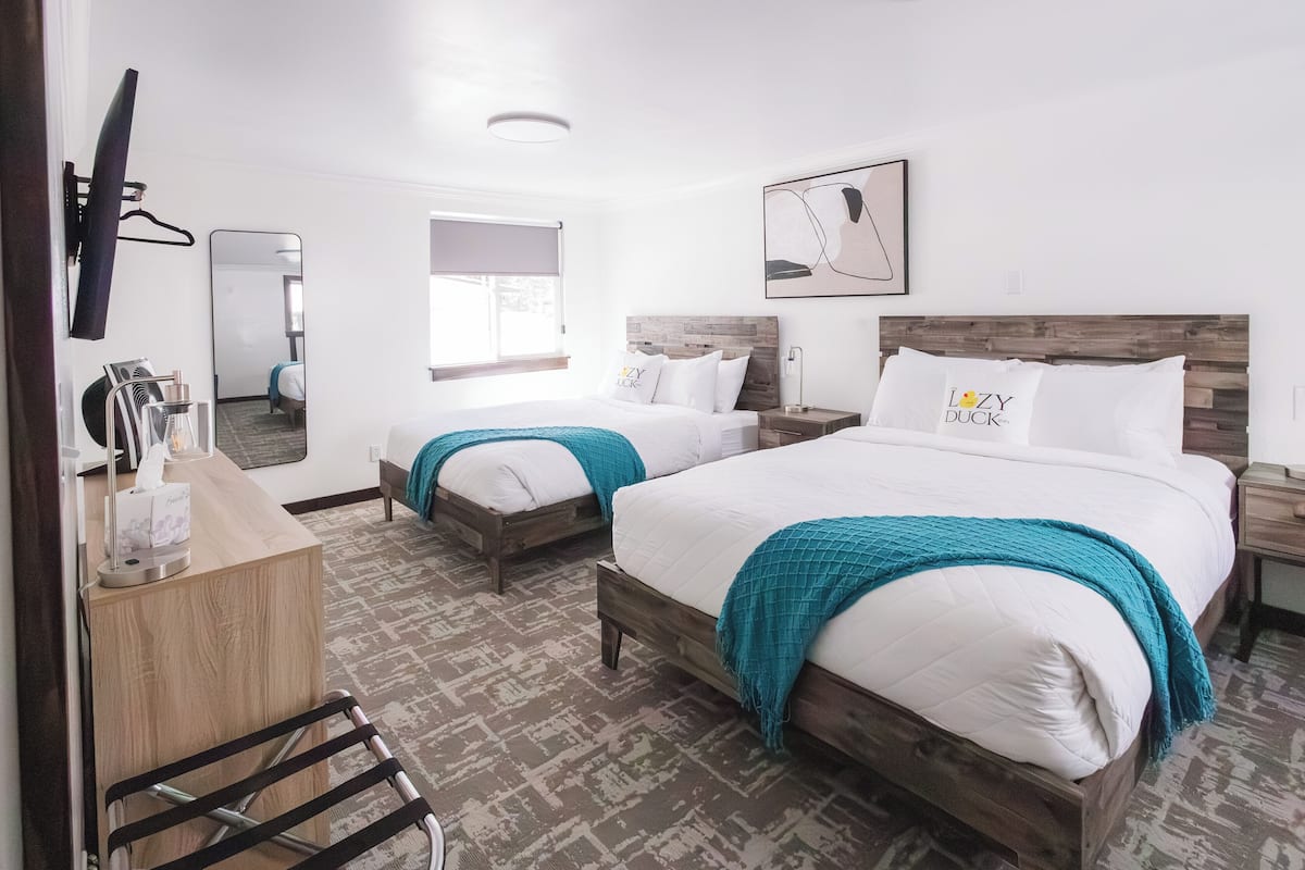 Une chambre d’hôtel avec deux lits, un bureau, un miroir et une télévision.