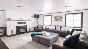 Ein modernes Wohnzimmer mit Kamin, Sofas, einem Couchtisch und Kunstwerken an den Wänden.