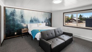 Ein Schlafzimmer mit einem Bett, einer schwarzen Ledersofa, einem großen Fenster und einem Wandbild von einem Wald.