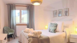 A neatly arranged hotel room with a bed, a desk, and a chair.