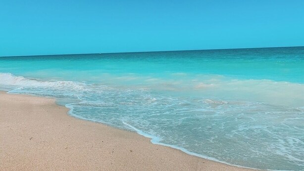 Une plage à l’eau turquoise et limpide, bordée d’un rivage sablonneux.
