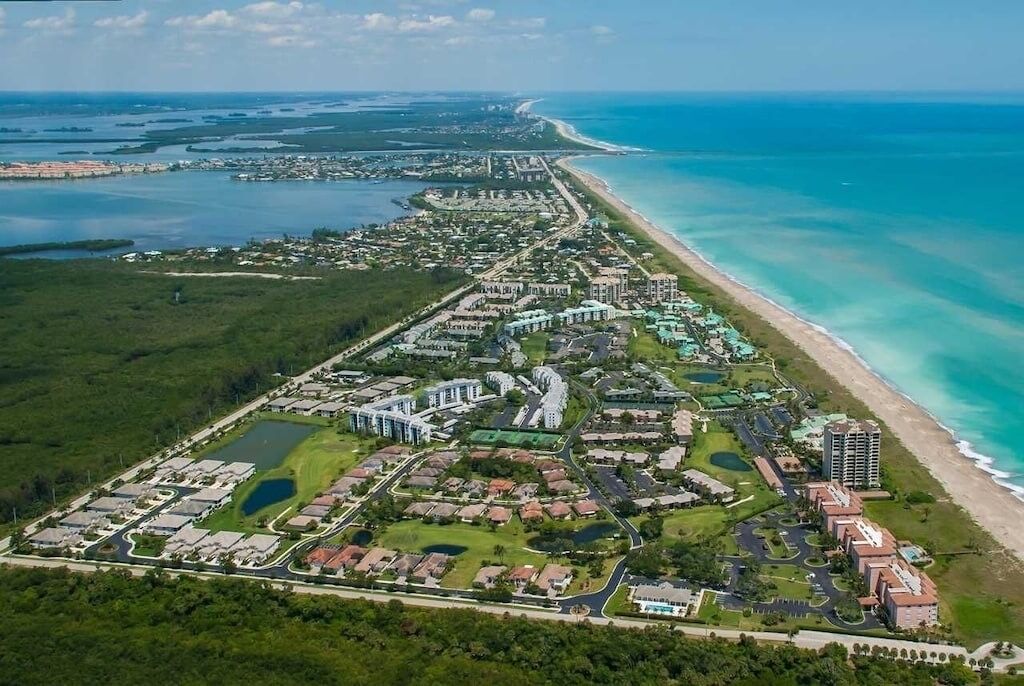 Vista aérea de um resort costeiro com vários edifícios, estradas e áreas verdes.