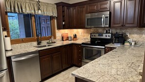 A kitchen with dark wooden cabinets, stainless steel appliances, and a granite countertop.