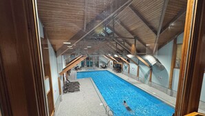 An indoor swimming pool with a tiled floor, a diving board, and a no diving sign on the wall.