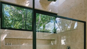 A modern shower with a glass door, wooden floor, and a view of trees outside. - Cozy Jungle Retreat, Private Indoor Pool, Breakfast, 5 mins to the Beach (San Miguel de Cozumel)