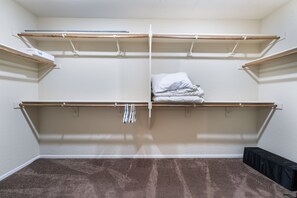 Habitación con armario empotrado con amplias repisas y barras para colgar ropa.