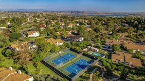 Ein Wohngebiet mit Tennisplatz, umgeben von Häusern und Grünflächen.