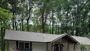 A single-story house with a gravel driveway, a wooden porch, and a small garden area with plants and a bench. - New Guest suite located in Jasper with a mountian view and fire pit (Jasper)