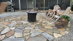 A stone patio with a fire pit, outdoor seating, and a large umbrella. - New Guest suite located in Jasper with a mountian view and fire pit (Jasper)