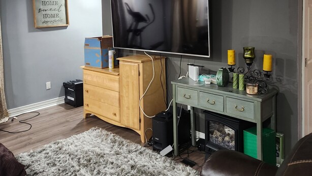 A living room with a flat-screen TV, wooden cabinet, and a ceiling fan.