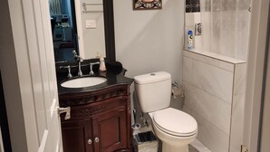 A bathroom with a white toilet, a sink with a dark countertop, and a shower curtain.