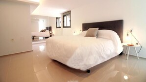 A modern bedroom with a large bed, a bedside table, and a mirror.