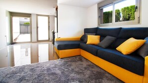 A modern living room with a sectional sofa, a large window, and a view of the outdoors.