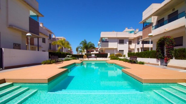 A swimming pool surrounded by modern buildings, with steps leading into the water.