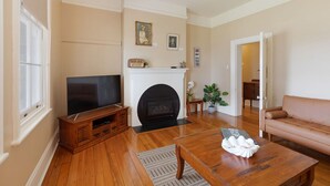 A living room with a fireplace, television, and a sofa. - Reflections Norah Head Lighthouse Cottages (Norah Head)
