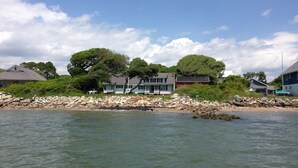 A coastal property with a stone wall, houses, and trees.