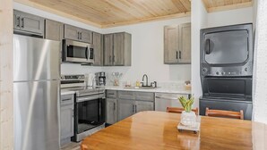 Una cocina moderna con electrodomésticos de acero inoxidable, techo de madera y una mesa de comedor con sillas.
