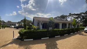 A building with a tiled roof and multiple windows, surrounded by a paved driveway and greenery. - Sega Lodge (Sega)
