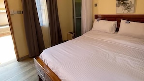 A bedroom with a large bed, wooden headboard, and a small bedside table. - Sega Lodge (Sega)