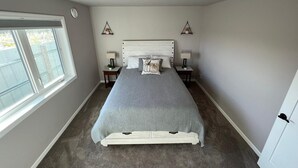 A bedroom with a large bed, two bedside tables with lamps, a window, and a ceiling light. - Experience Fairbanks comfortably, just a 3-min drive from Creamer's Field (Fairbanks)