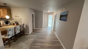A spacious kitchen with a wooden countertop and bar stools, a hallway with hardwood flooring, and a painting on the wall. - Experience Fairbanks comfortably, just a 3-min drive from Creamer's Field (Fairbanks)