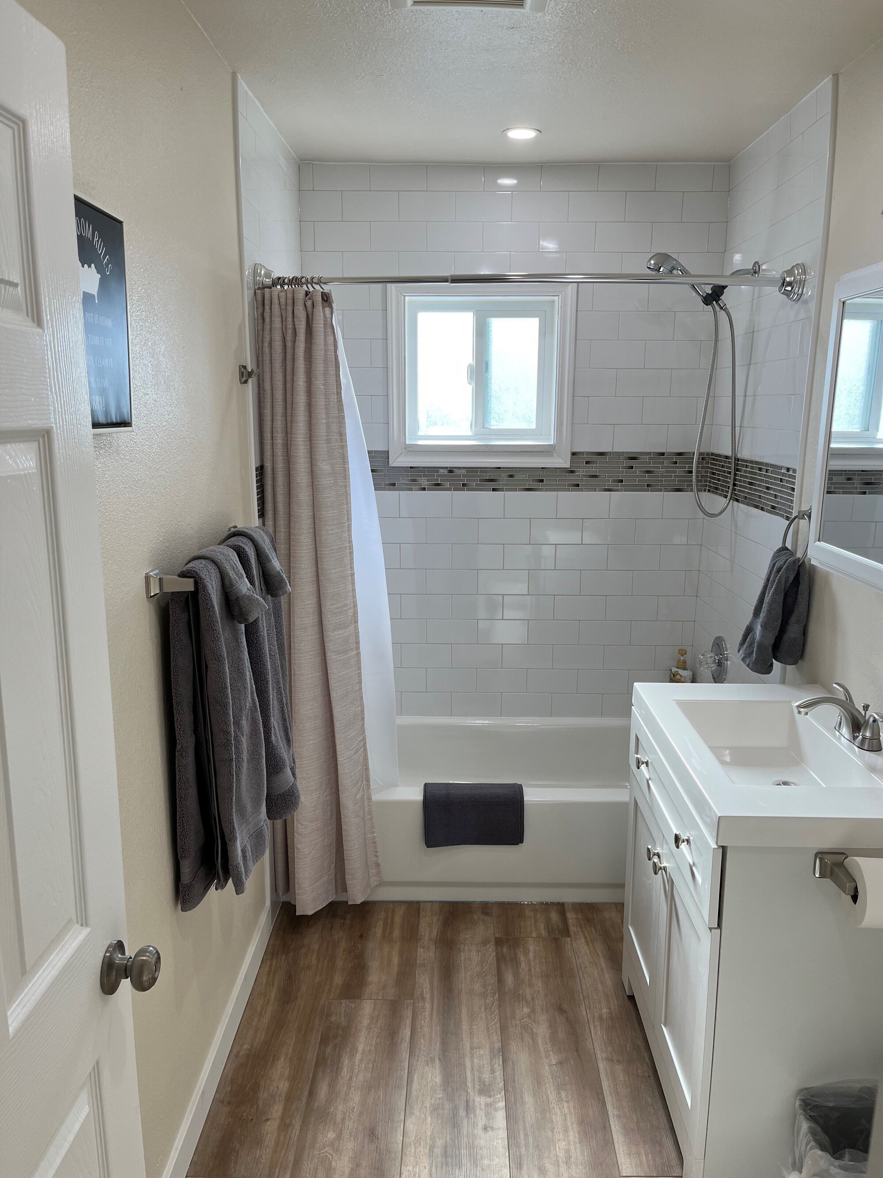 Ein Badezimmer mit Badewanne, Dusche, Fenster und Waschbecken.