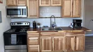 Una cucina moderna con mobili in legno, un fornello in acciaio inossidabile, un forno a microonde e una macchina per il caffè.