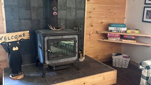 Ein gemütliches Zimmer mit Kaminofen, einer Willkommensanzeige und einem Regal mit Gesellschaftsspielen.