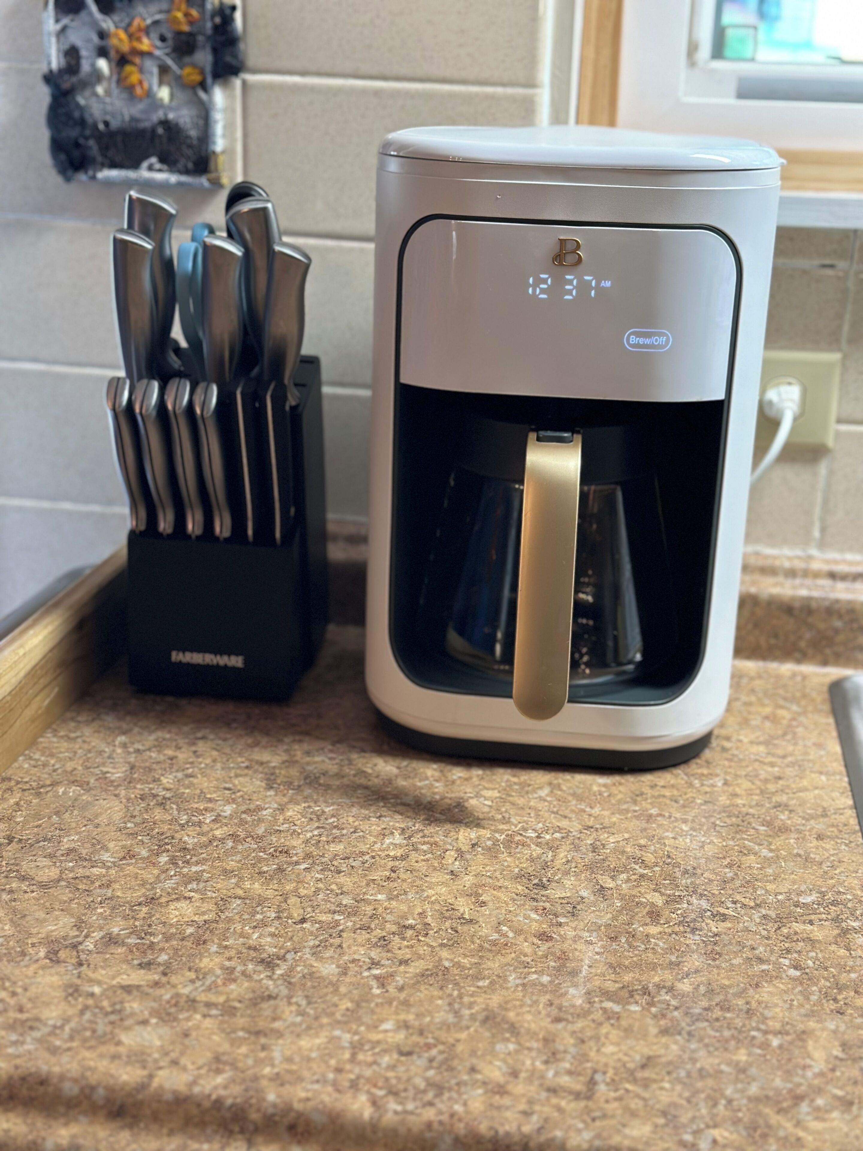 A coffee maker with a timer set to 12:31 AM on a kitchen counter.