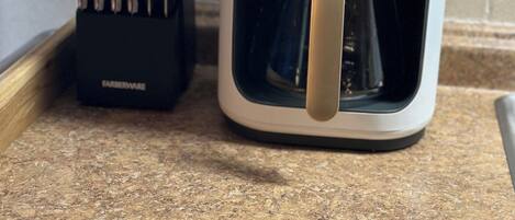 A coffee maker with a timer set to 12:31 AM on a kitchen counter.